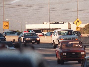 LOS ANGELES - JUNE 17:  Motorists wave as police cars pursue the Ford Bronco (white, R) driven by Al Cowlings, carrying fugitive murder suspect O.J. Simpson, on a 90-minute slow-speed car chase June 17, 1994 on the 405 freeway in Los Angeles, California. Simpson's friend Cowlings eventually drove Simpson home, with Simpson ducked under the back passenger seat, to Brentwood where he surrendered after a stand-off with police. (Photo credit should read MIKE NELSON/AFP via Getty Images)