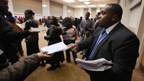Cory Thames, with the city of Chicago human resources department, collects resumes from Job seekers as they enter a job fair being held at Kennedy-King College and hosted by the city of Chicago on November 9, 2012 in Chicago, Illinois. Thousands of people waited in line beginning at 3AM for the job fair which did not open the doors until 9AM. When the doors opened the line was about a half-mile long. (Photo by Scott Olson/Getty Images)