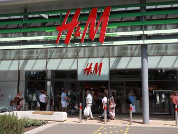 RUSHDEN, UNITED KINGDOM - JUNE 15:  Queues form at H&M store at the Rushden Lakes shopping complex on June 15, 2020 in Rushden, United Kingdom. The British government have relaxed coronavirus lockdown laws significantly from Monday June 15, allowing zoos, safari parks and non-essential shops to open to visitors.  Places of worship will allow individual prayers and protective facemasks become mandatory on London Transport.  (Photo by David Rogers/Getty Images)