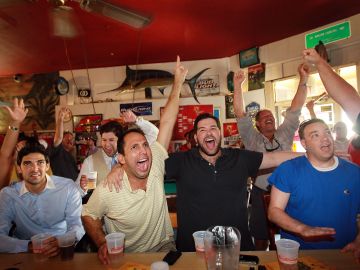 MIAMI - JUNE 23:  Frank Mena (2L), Ricardo Martinez (2R), Mark Kerr (R) and others celebrate the winning goal for the USA soccer team while watching the 2010 FIFA World Cup South Africa Group C match between USA and Algeria on television at Churchill's pub on June 23, 2010 in Miami, Florida.  The United States team will advance to the second round at the World Cup with a 1-0 win over Algeria.  (Photo by Joe Raedle/Getty Images)