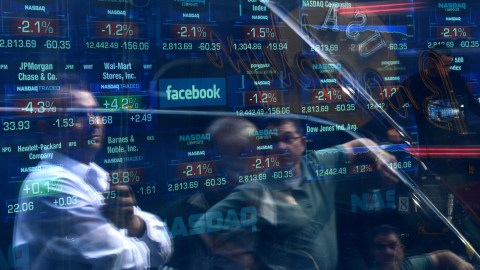 A Facebook logo is seen through the windows of the NASDAQ stock exchange as people walk by on Times Square in New York, May 17, 2012. Facebook is set to go public on May 18, 2012 and is likely to have an estimated market valuation of over 100 billion USD when its shares begin trading on the NASDAQ. AFP PHOTO/Emmanuel Dunand (Photo credit should read EMMANUEL DUNAND/AFP/GettyImages)