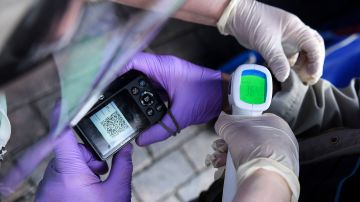 An employee checks the temperature of a visitor at the entrance of the annual book fair on the Red Square in downtown Moscow on June 6, 2020. - The open-air book fair is the first public event since the country eased lockdown measures taken to curb the spread of the COVID-19 pandemic, caused by the novel coronavirus. (Photo by Kirill KUDRYAVTSEV / AFP) (Photo by KIRILL KUDRYAVTSEV/AFP via Getty Images)