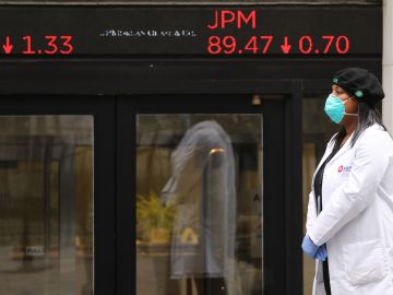 NEW YORK, NEW YORK - MAY 26: A medical worker stands at the entrance to the New York Stock Exchange (NYSE) on the first day that traders are allowed back onto the historic floor of the exchange on May 26, 2020 in New York City. While only a small number of traders will be returning at this time, those that do will have to take temperature checks and wear face masks at all times while on the floor. The Dow rose over 600 points in morning trading as investors see economic activity in America picking up (Photo by Spencer Platt/Getty Images)