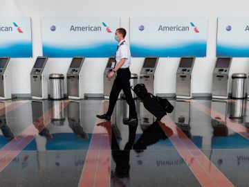 An airline employee walks past empty American Airlines check-in terminals at Ronald Reagan Washington National Airport in Arlington, Virginia, on May 12, 2020. - The airline industry has been hit hard by the COVID-19 pandemic, with the number of people flying having decreased by more than 90 percent since the beginning of March. (Photo by ANDREW CABALLERO-REYNOLDS / AFP) (Photo by ANDREW CABALLERO-REYNOLDS/AFP via Getty Images)