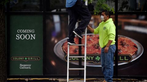 Men wearing face masks work in front of a restaurant in Arlington, Virginia on May 28, 2020. - Northern Virginia and Washington, DC, will begin relaxing the coronavirus pandemic shutdown on businesses on May 29. Another 2.12 million people filed for unemployment in the US last week, pushing total layoffs since the start of the coronavirus crisis to more than 40 million, a level not seen since the Great Depression, the Labor Department said on May 28. The new filings, however, showed that the pace of the layoffs was subsiding as the US economy slowly begins to reopen. (Photo by Olivier DOULIERY / AFP) (Photo by OLIVIER DOULIERY/AFP via Getty Images)