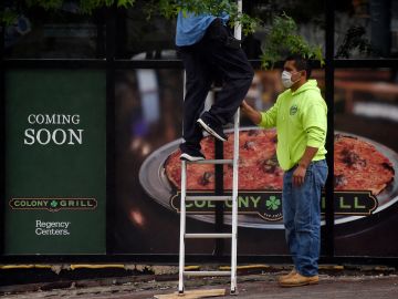 Men wearing face masks work in front of a restaurant in Arlington, Virginia on May 28, 2020. - Northern Virginia and Washington, DC, will begin relaxing the coronavirus pandemic shutdown on businesses on May 29. Another 2.12 million people filed for unemployment in the US last week, pushing total layoffs since the start of the coronavirus crisis to more than 40 million, a level not seen since the Great Depression, the Labor Department said on May 28. The new filings, however, showed that the pace of the layoffs was subsiding as the US economy slowly begins to reopen. (Photo by Olivier DOULIERY / AFP) (Photo by OLIVIER DOULIERY/AFP via Getty Images)