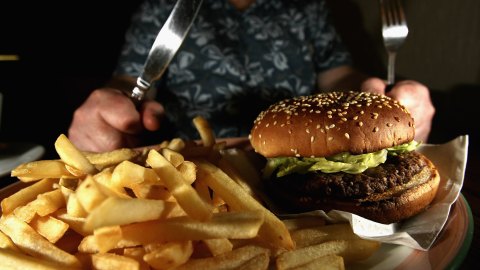 GLASGOW, UNITED KINGDOM - JUNE 07: In this photo illustration a man eats a hamburger ind chips in a cafe on June 7,2006 in Glasgow, Scotland. New figures are suggesting that a large proportion of the population is clinically obese. (Photo Illustration by Jeff J Mitchell/Getty Images)