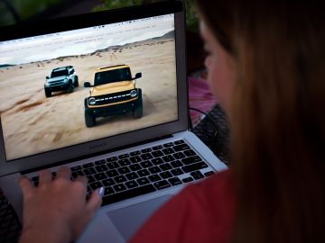 This illustration picture shows a person watching the 2021 Ford Bronco Family World Premiere on a computer in Arlington, Virginia on July 13, 2020. - US automaker Ford unveiled new versions of its legendary Bronco 4x4 on July 13, hoping to attract a new generation of enthusiasts 24 years after it stopped production and enter into direct competition with Fiat Chrysler's Jeep. (Photo by Olivier DOULIERY / AFP) (Photo by OLIVIER DOULIERY/AFP via Getty Images)