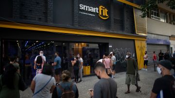 People queue at a gym in Lapa neighbourhood in Rio de Janeiro, Brazil, on July 2, 2020 as the city's bars and restaurants reopened after more than three months of lockdown to fight the COVID-19 novel coronavirus pandemic. - Rio de Janeiro's bars and restaurants reopened despite criticism by health specialists in Brazil, one of the world's worst-hit nations. As part of a phased return to normality, bars, restaurants and cafes are authorized to reopen to 50 percent capacity, with a distance of two metres between tables and priority given to open-air dining and drinking. Rio's gyms, beauty and tattoo parlors may also open on a staggered basis, to avoid crowding. (Photo by Mauro PIMENTEL / AFP) (Photo by MAURO PIMENTEL/AFP via Getty Images)