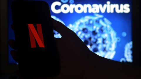 In this photo illustration  a mobile phone screens display the Netflix logo on a coronavirus COVID-19 illustration graphic background , March 31, 2020 in Arlington, Virginia. (Photo by Olivier DOULIERY / AFP) (Photo by OLIVIER DOULIERY/AFP via Getty Images)