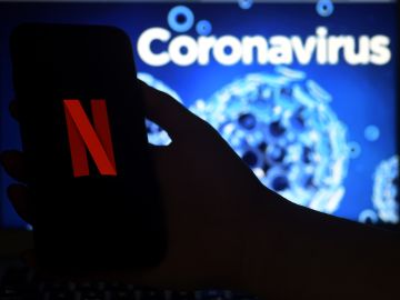 In this photo illustration  a mobile phone screens display the Netflix logo on a coronavirus COVID-19 illustration graphic background , March 31, 2020 in Arlington, Virginia. (Photo by Olivier DOULIERY / AFP) (Photo by OLIVIER DOULIERY/AFP via Getty Images)