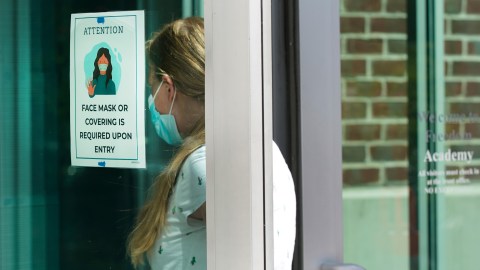 PROVO, UT - AUGUST 13: With a mask sign on the door a teacher walks into Freedom Preparatory Academy as they begin to prepare to restart school after it was closed in March due to COVID-19 on August 13, 2020 in Provo, Utah. The school is planning to have students return on August 18 for five days a week instruction, but with reduced hours during the day. (Photo by George Frey/Getty Images)