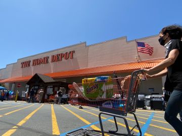 A shopper wearing a facemask pushes her cart while people wait in line to enter The Home Depot in Marina Del Rey, California on May 22, 2020, amid the novel coronavirus pandemic. (Photo by Chris DELMAS / AFP) (Photo by CHRIS DELMAS/AFP via Getty Images)