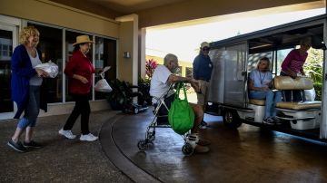 Elderly residents get into a buggie inside deserted John Knox Village, a retirement community in Pompano Beach, Florida on March 21, 2020. - Almost one billion people were confined to their homes worldwide as the global coronavirus death toll topped 12,000 and US states rolled out stay-at-home measures already imposed across swathes of Europe. More than a third of Americans were adjusting to life in various phases of virtual lockdown -- including in the US's three biggest cities of New York, Los Angeles and Chicago -- with more states expected to ramp up restrictions. (Photo by CHANDAN KHANNA / AFP) (Photo by CHANDAN KHANNA/AFP via Getty Images)