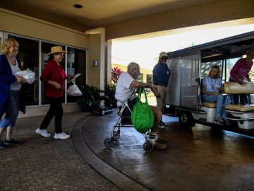 Elderly residents get into a buggie inside deserted John Knox Village, a retirement community in Pompano Beach, Florida on March 21, 2020. - Almost one billion people were confined to their homes worldwide as the global coronavirus death toll topped 12,000 and US states rolled out stay-at-home measures already imposed across swathes of Europe. More than a third of Americans were adjusting to life in various phases of virtual lockdown -- including in the US's three biggest cities of New York, Los Angeles and Chicago -- with more states expected to ramp up restrictions. (Photo by CHANDAN KHANNA / AFP) (Photo by CHANDAN KHANNA/AFP via Getty Images)