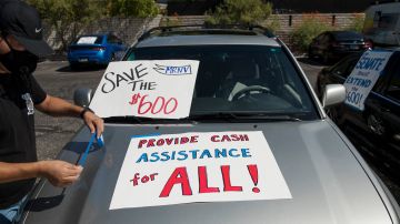 A man tapes signs to his car before participating in a caravan rally down the Las Vegas Strip in support of extending the $600 unemployment benefit, August 6, 2020 in Las Vegas, Nevada. (Photo by Bridget BENNETT / AFP) (Photo by BRIDGET BENNETT/AFP via Getty Images)
