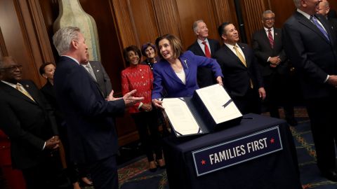 WASHINGTON, DC - MARCH 27: Speaker of the House Nancy Pelosi (D-CA), surrounded by a bipartisan group of members of the House, shows off the stimulus bill known as the CARES Act after the bill was passed at the U.S. Capitol on March 27, 2020 in Washington, DC. The stimulus bill is intended to combat the economic effects caused by the coronavirus pandemic. (Photo by Win McNamee/Getty Images)