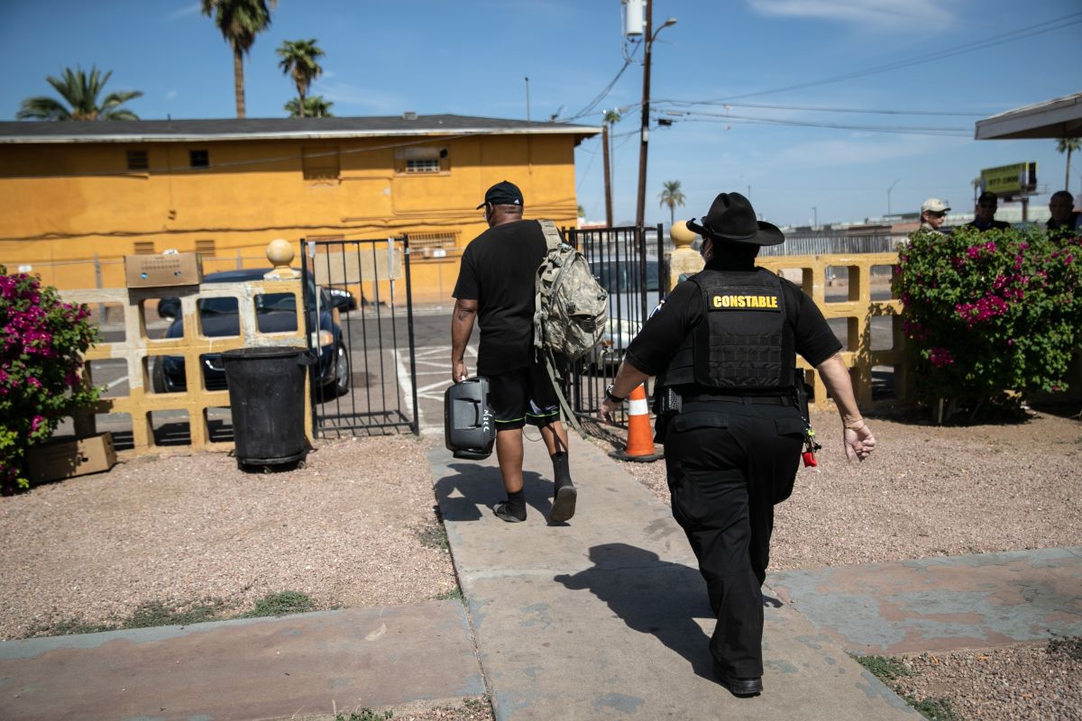 Un hombres es acompañado por un alguacil durante un desalojo en Maricopa, Arizona.