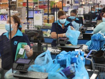 MIAMI, FLORIDA - APRIL 13: Diana Rivero stands behind a partial protective plastic screen and wears a mask and gloves as she works as a cashier at the Presidente Supermarket on April 13, 2020 in Miami, Florida. The employees at Presidente Supermarket, like the rest of America's grocery store workers, are on the front lines of the coronavirus pandemic, helping to keep the nation's residents fed. (Photo by Joe Raedle/Getty Images)