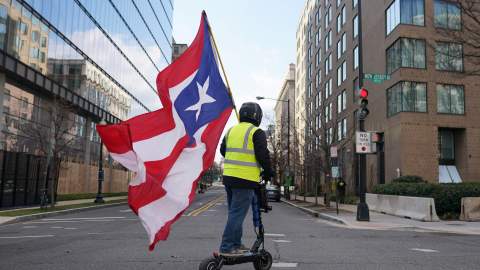 WASHINGTON, DC - JANUARY 20: A man waving the Puerto Rico flag rides a scooter down New Jersey Avenue following the inauguration of President Joe Biden on January 20, 2021 in Washington, DC.