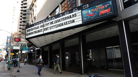 NEW YORK, NEW YORK - NOVEMBER 19: People wearing protective masks walk by a closed movie theater on November 19, 2020 in New York City. The pandemic has caused long-term repercussions throughout the tourism and entertainment industries, including temporary and permanent closures of historic and iconic venues, costing the city and businesses billions in revenue. (Photo by Cindy Ord/Getty Images)