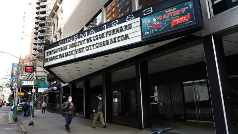 NEW YORK, NEW YORK - NOVEMBER 19: People wearing protective masks walk by a closed movie theater on November 19, 2020 in New York City. The pandemic has caused long-term repercussions throughout the tourism and entertainment industries, including temporary and permanent closures of historic and iconic venues, costing the city and businesses billions in revenue. (Photo by Cindy Ord/Getty Images)