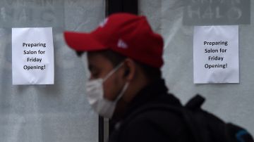 A man, wearing a face mask, walks past a hair salon ready to reopen in Arlington, Virginia, on May 28, 2020. - Northern Virginia and Washington, DC, will begin relaxing the coronavirus pandemic shutdown on businesses on May 29. Another 2.12 million people filed for unemployment in the US last week, pushing total layoffs since the start of the coronavirus crisis to more than 40 million, a level not seen since the Great Depression, the Labor Department said on May 28. The new filings, however, showed that the pace of the layoffs was subsiding as the US economy slowly begins to reopen. (Photo by Olivier DOULIERY / AFP) (Photo by OLIVIER DOULIERY/AFP via Getty Images)