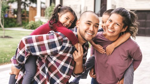 Parents carrying children piggyback outdoor