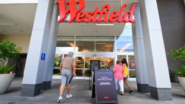 People walk past a sign reminding shoppers of the mask requirement while entering the Westfield Santa Anita shopping  mall on June 12, 2020 in Arcadia, California, as Phase 3 in Los Angeles County's battle with the coronavirus pandemic is underway with businesses reopening. (Photo by Frederic J. BROWN / AFP) (Photo by FREDERIC J. BROWN/AFP via Getty Images)