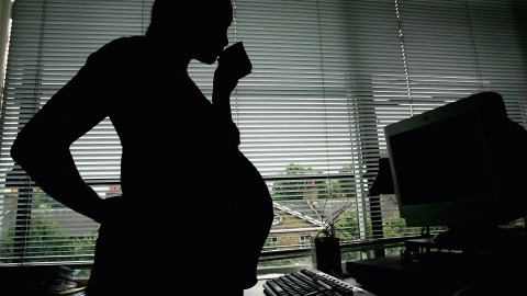 LONDON - JULY 18: In this photo illustration a pregnant woman is seen stood at the office work station on July 18, 2005 in London, England. Under plans to revise paid maternity leave, an exteneded period of six to nine months will be offered for maternity leave from 2007. (Photo illustration by Daniel Berehulak/Getty Images)