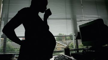 LONDON - JULY 18:  In this photo illustration a pregnant woman is seen stood at the office work station on July 18, 2005 in London, England. Under plans to revise paid maternity leave, an exteneded period of six to nine months will be offered for maternity leave from 2007. (Photo illustration by Daniel Berehulak/Getty Images)