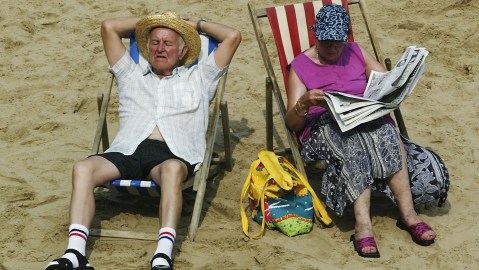 BLACKPOOL, ENGLAND - AUGUST 6: An elderly couple soak up the sun on Blackpool beach August 6, 2003 in Blackpool, England. The temperature in the UK peaked at 35.9 degrees Celsius today, making it the hottest day of the year so far. (Photo by Michael Steele/Getty Images)