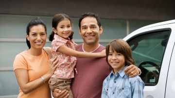 Family standing outside house next to car
