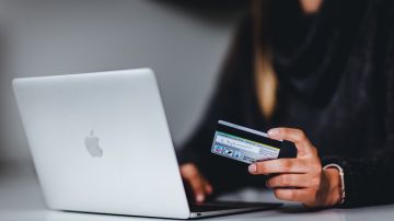 Foto de una persona usando una tarjeta de crédito y una laptop