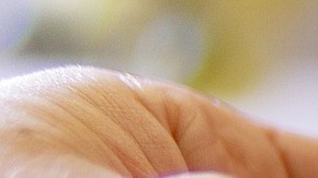 Foto de la mano de una persona sosteniendo una tarjeta frente a una laptop