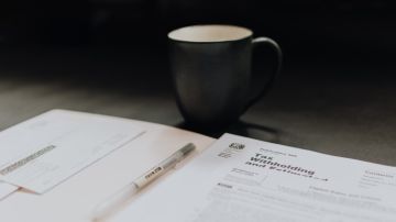 Foto de varios formularios de de declaración de impuestos junto a una taza de café