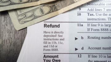 Foto de un formulario de declaración de impuestos junto a billetes de 20 dólares