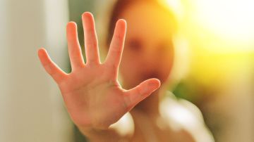 Foto de una mujer mostrando la palma de su mano en señal de stop