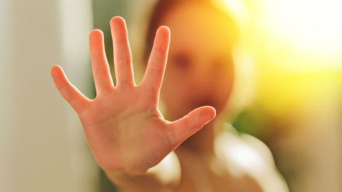 Foto de una mujer mostrando la palma de su mano en señal de stop