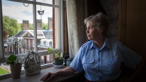 Foto de una mujer mayor mirando desde su ventana