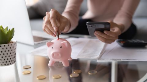 Foto de una mujer usando una alcancía para representar el ahorro