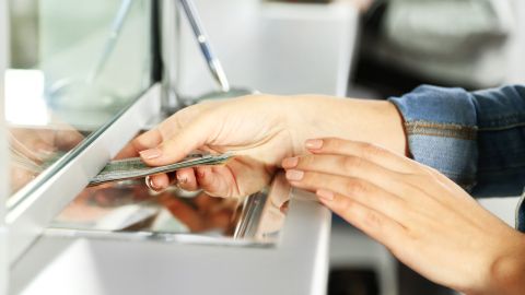 Foto de una persona realizando una transacción en la taquilla de un banco