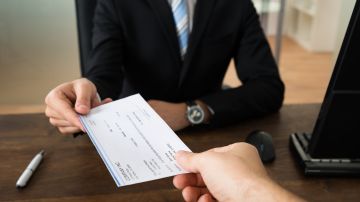 Foto de una persona entregando un cheque a otra persona