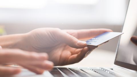 Foto de la mano de una persona sosteniendo una tarjeta de crédito sobre una laptop