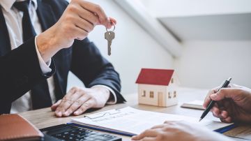 Foto de un hombre entregando las llaves de una casa durante la firma de un contrato