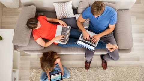 Foto de una familia usando sus dispositivos electrónicos