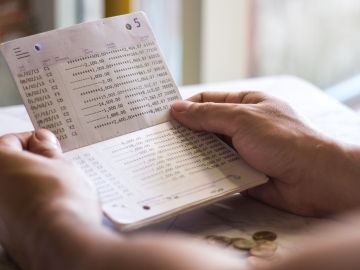 Foto de las manos de una personas sosteniendo una libreta de ahorros de un banco