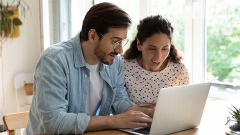 Foto de una pareja en actitud de sorpresa frente a una laptop