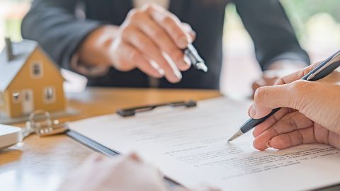 Foto de dos personas firmando un contrato relacionado con una casa