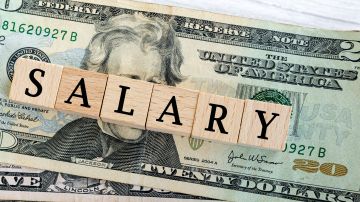 Foto de la palabra "salary" escrita con bloques de madera sobre dólares
